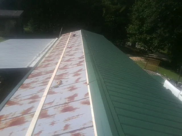 Old rusted panels beside newly installed green metal roofing — Wind Damage Roof Repair by Roofing Brothers in Crum Lynne
