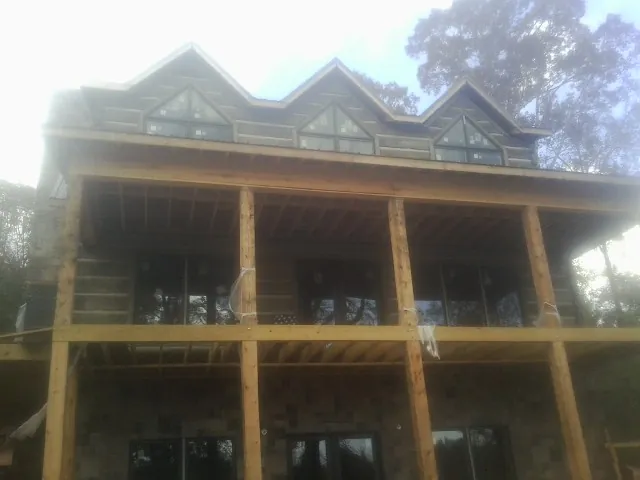 Dormers and porch framing on a large log home under construction — Roof Coating work by our crew in Crum Lynne