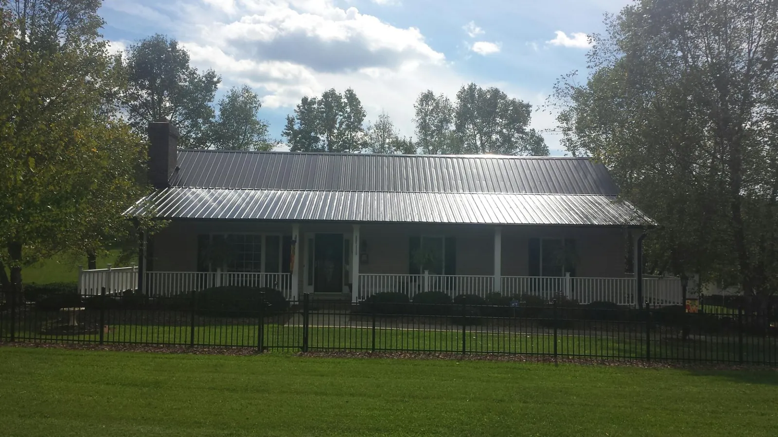 Gray metal roof on a brick ranch with a full width front porch — Gutter Guard Installation work by our crew in Crum Lynne