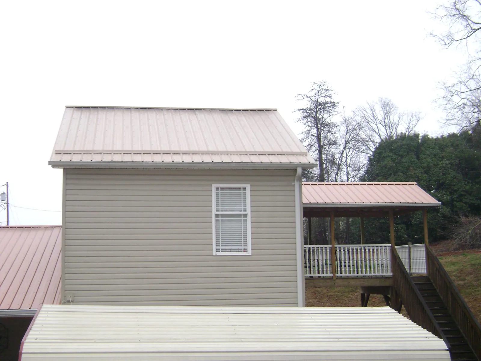 Tan metal roofs on a two story addition and attached porch, from a Roof Replacement job in Crum Lynne
