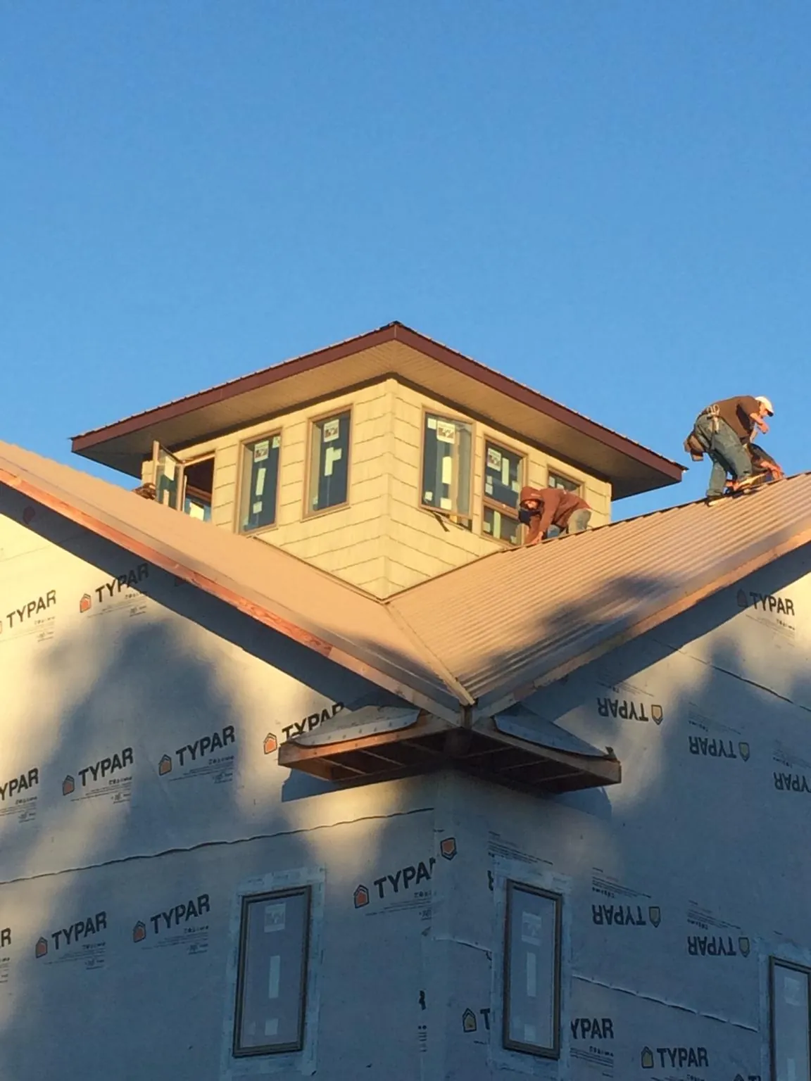 Roofers working around a rooftop cupola on a new metal roof at sunset — Roof Waterproofing in Crum Lynne by Roofing Brothers